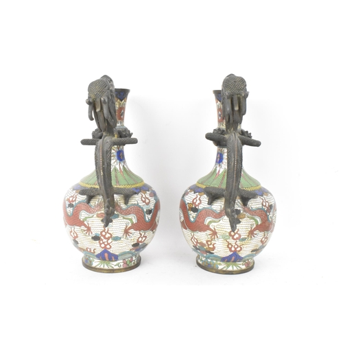 109 - A pair of Chinese late Qing dynasty cloisonne ewers, both having a handle modelled in the form of a ... 