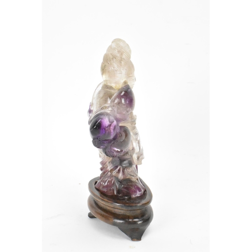 139 - A 20th century Chinese carved amethyst figure of Guanyin, the goddess of mercy, in a seated position... 