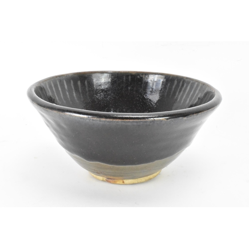 141 - A Chinese Cizhou type bowl, of conical form and covered in a dark lustrous glaze falling short of th... 