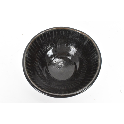 141 - A Chinese Cizhou type bowl, of conical form and covered in a dark lustrous glaze falling short of th... 