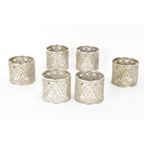 149 - A set of six early 20th century Middle Eastern white metal filigree napkin rings, elaborately pierce... 