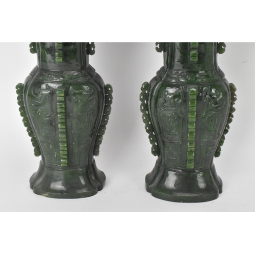 31 - A pair of Chinese 20th century jadeite vases, of flattened baluster shape with archaistic relief dec... 