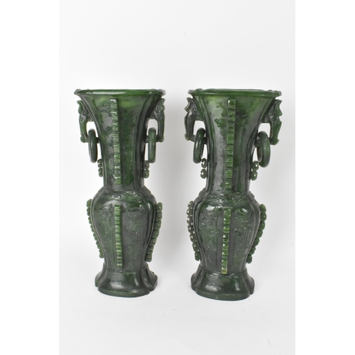 31 - A pair of Chinese 20th century jadeite vases, of flattened baluster shape with archaistic relief dec... 