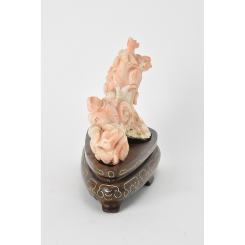 33 - A Chinese 20th century coral carving depicting a laughing Buddha with child among a nautical scenery... 