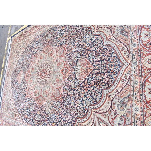 155 - An early 20th century handwoven Indian Agra rug, with central floral medallion on a navy ground, wit... 