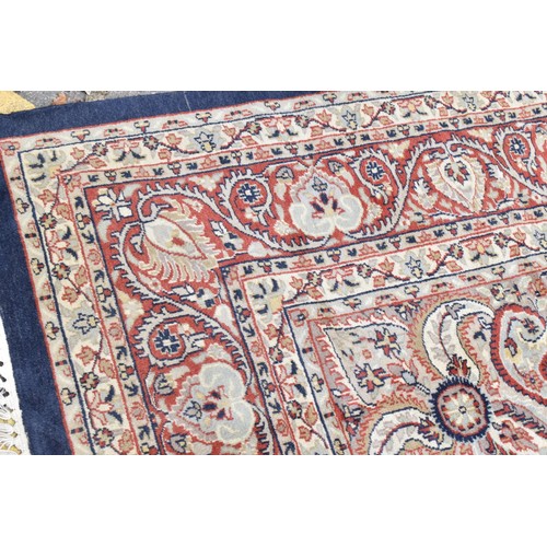 155 - An early 20th century handwoven Indian Agra rug, with central floral medallion on a navy ground, wit... 