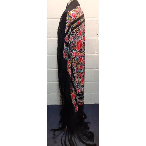 27 - An early 20th century machine embroidered black Oriental shawl with vibrant images of roses, wild fl... 