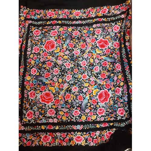 27 - An early 20th century machine embroidered black Oriental shawl with vibrant images of roses, wild fl... 