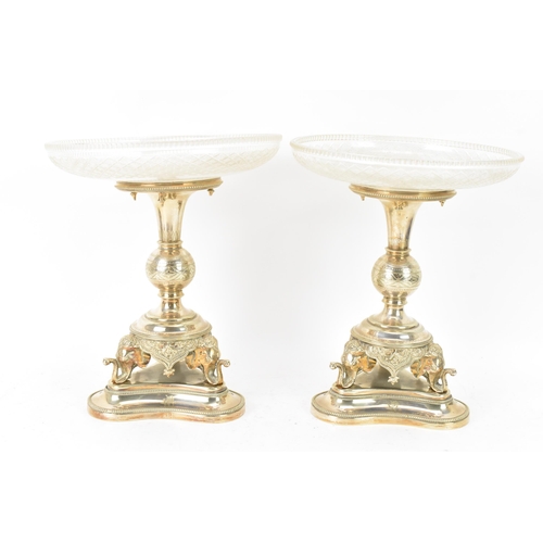 103 - A pair of late Victorian silver plated pedestal dishes, each having cut glass dishes raised by a kno... 