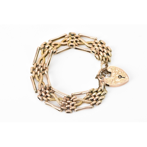 125 - A 9ct gold gate link bracelet, having a heart shaped locket with engraved detail and a safety chain,... 