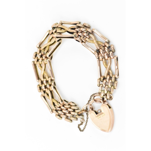 125 - A 9ct gold gate link bracelet, having a heart shaped locket with engraved detail and a safety chain,... 