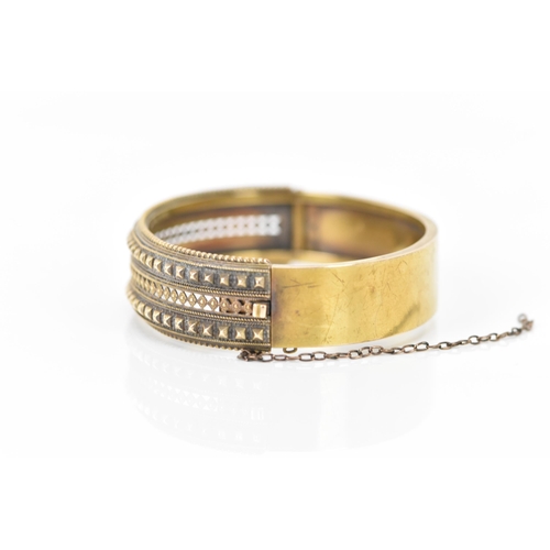 132 - A late Victorian 15ct yellow gold etruscan revival hinged bangle, circa 1880, having beaded rim, pie... 