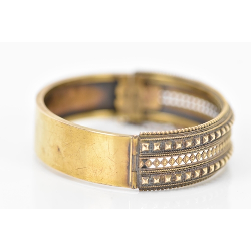 132 - A late Victorian 15ct yellow gold etruscan revival hinged bangle, circa 1880, having beaded rim, pie... 