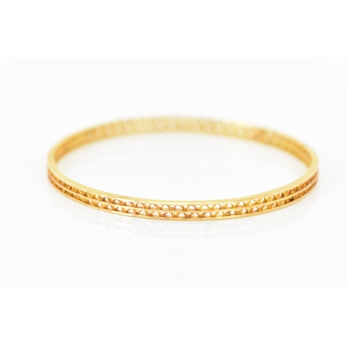 134 - An 18ct yellow gold bangle, having a pierced woven design and stamped N G F 18ct to the border, 7cm ... 