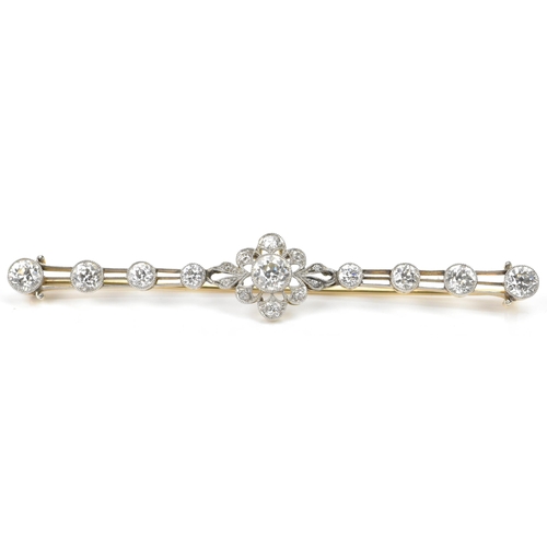 An early 20th century platinum and yellow gold diamond bar brooch, designed with a central floral cluster comprising a central diamond surrounded by ten melee diamonds, flanked by a further eight diamonds graduating along triple polished arms, 93.4mm x 2.8mm wide x 2.6mm depth, 9.8 grams

Provenance: 
Belonged to the vendors aunts Grandmother, photograph included of her wearing the brooch  during presentation to Queen Mary at Belfast City Hall. Photocopy of insurance and probate valuation included.

Diamond details:
The central stone colour H/I, clarity SI1/SI2, approx 1.33ct, the two outer stones colour G/H, clarity VS1/VS2, approx 0.9ct, the two stones third along colour H/I VS2/SI1, approx 0.55ct, the two stones two along colour I/J, clarity SI1/SI2, approx 0.39, the two stones flanking the brooch colour H/I, clarity SI1/SI2, approx 0.28ct.