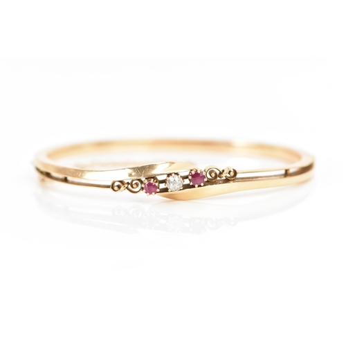 259 - A 14ct gold diamond and ruby bangle, the central brilliant cut diamond approx 3.5mm flanked by two r... 