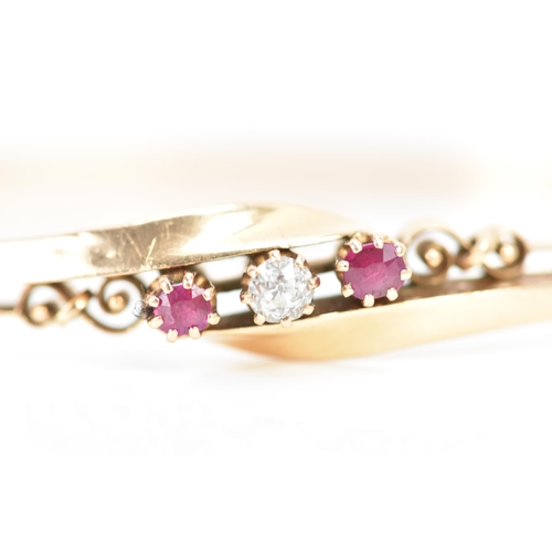 259 - A 14ct gold diamond and ruby bangle, the central brilliant cut diamond approx 3.5mm flanked by two r... 