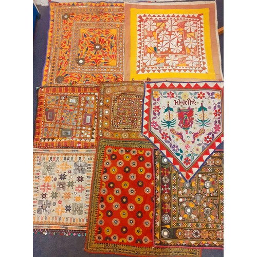 128 - A group of traditional hand embroidered Indian decorative items to include Banjari textile panels wi... 