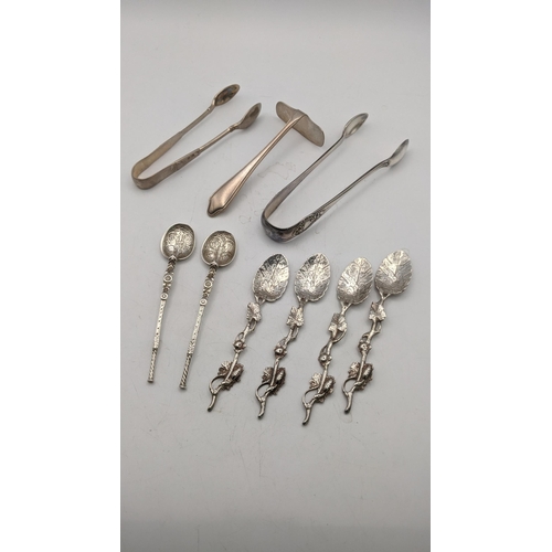 133 - Two pairs of sugar tongs, a silver pusher, a pair of decorative coffee spoons and four white metal s... 