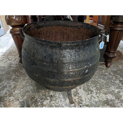 278 - A cast iron twin handled cooking pot on a wrought iron stand A/F Location: G If there is no conditio... 