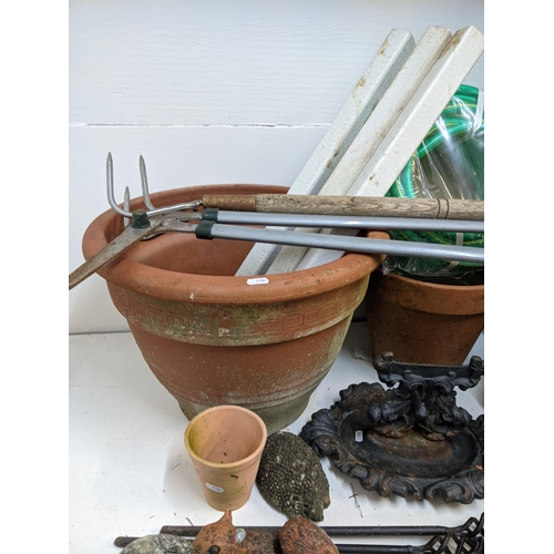 331 - Garden related items to include pots, garden ornaments, a boot scraper, an unused hose, wooden stake... 