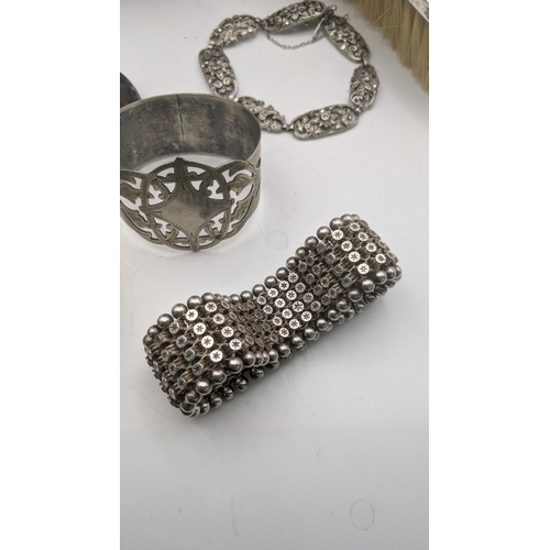 98 - A group of silver and white metal jewellery to include a silver hinged bangle with engraved floral d... 