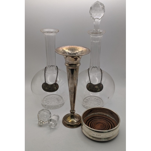 152 - Silver to include a bottle coaster, a weighted vase and a pair of decanter labels with glass decante... 