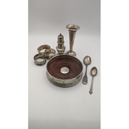 154 - Mixed silver items to include a wine coaster, a tulip vase, three napkin rings, two teaspoons and a ... 