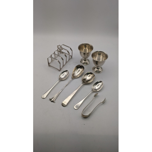 156 - Silver to include a pair of egg cups, a toast rack hallmarked Birmingham 1932, together with four sp... 