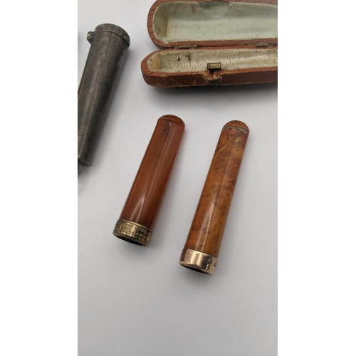 201A - Smoking related items to include two amber cheroots, one with an 18ct gold band and the other a ct g... 