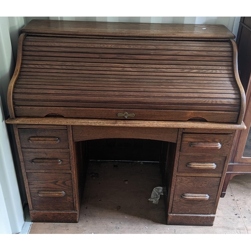 320 - An early/mid 20th century oak roll top desk having a fitted interior, drawer below and drawer pedest... 