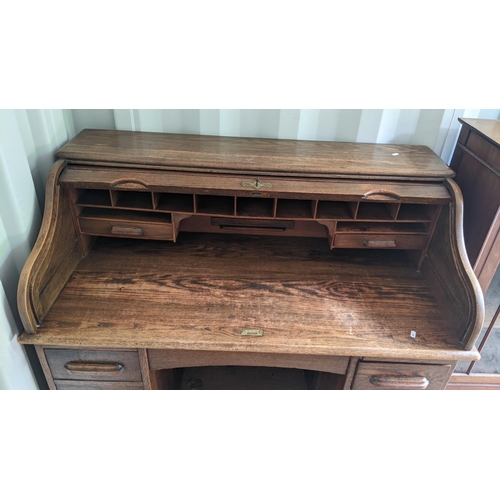 320 - An early/mid 20th century oak roll top desk having a fitted interior, drawer below and drawer pedest... 