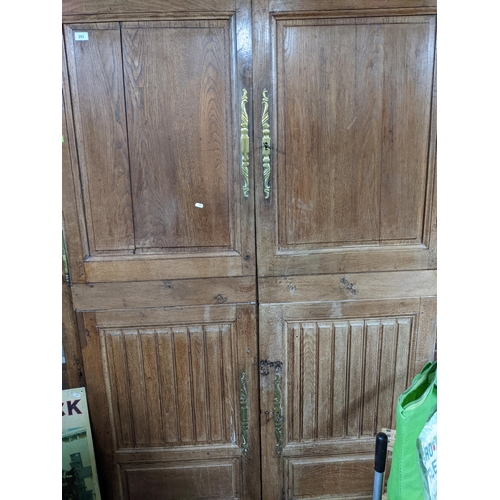 293 - An 18th century oak armoire, twin panelled and carved doors with brass escutcheons, shaped apron and... 