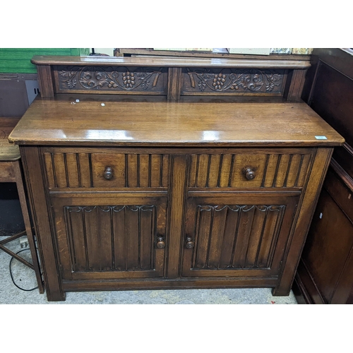 310 - An early to mid oak linenfold sideboard, extended back with two panels of grape and vine leaf carved... 