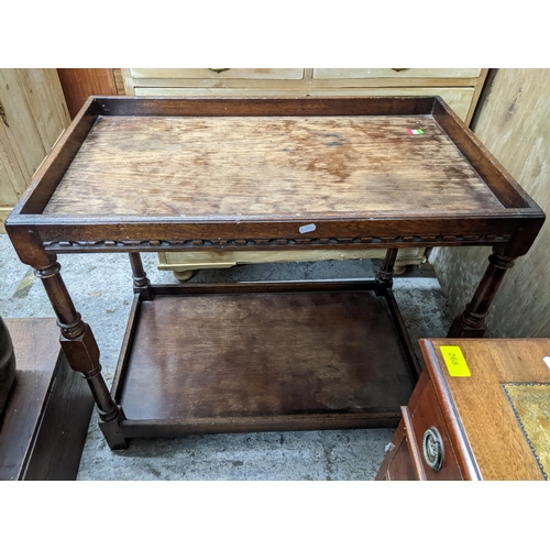 275 - A 20th century oak carved two tier tea trolley, galleried top and undertier, turned columns and bloc... 