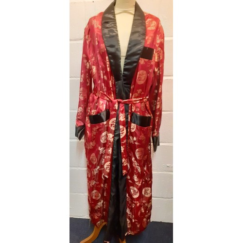 31 - A Chinese red and black smoking robe with machine printed gold embroidered images of dragons having ... 