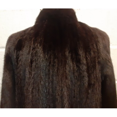 82 - A late 20th Century glossy black mink swing coat having a brown lining with fleur de lys embroidery ... 