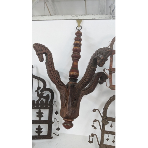 176 - Three Indian wall hanging oil lamp stands together with a wooden carved hanging centrepiece, and one... 