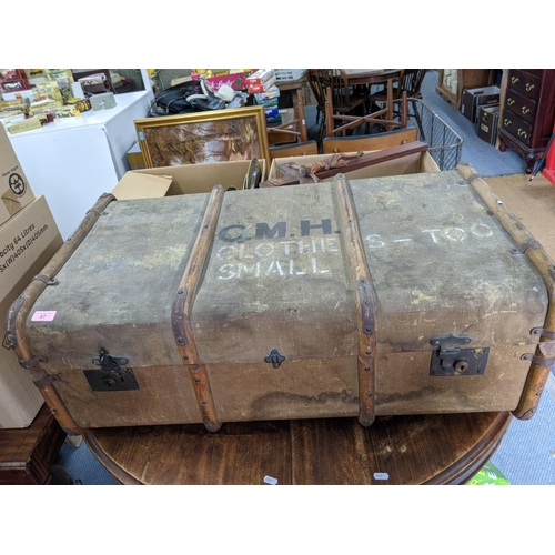 37 - A vintage canvas bound trunk with two locks at the front and a leather carrying handle at each end, ... 