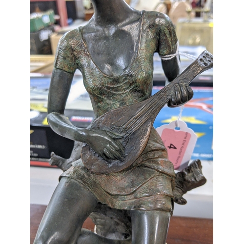 4 - A bronze composite figure of a lady playing a banjo sat on a tree stump on a naturalistic base, sign... 