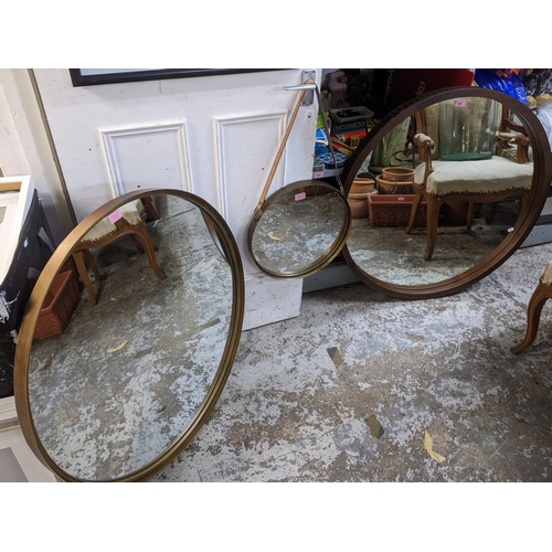 491 - A group of three modern circular framed wall mirrors, the largest framed in wood with blind fretwork... 