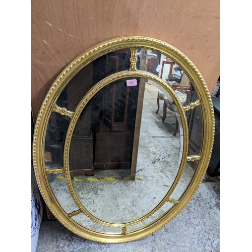 70 - A gilt framed oval wall mirror with bevelled central glass plate, surrounded by eight smaller panels... 