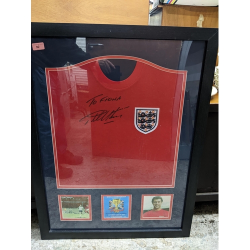 92 - A framed and glazed Geoff hurst autographed England football shirt with a montage of pictures below,... 