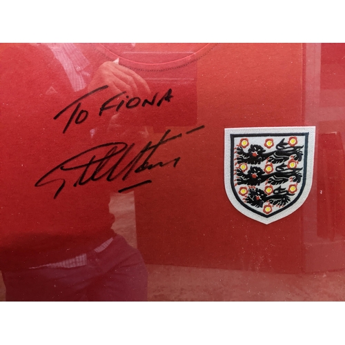 92 - A framed and glazed Geoff hurst autographed England football shirt with a montage of pictures below,... 