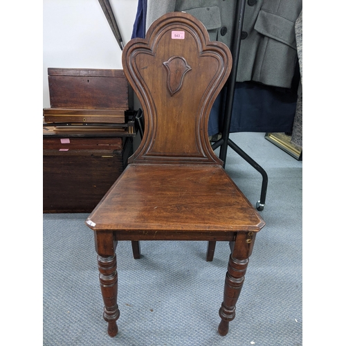 543 - A Victorian mahogany hall chair, the solid carved back with a shield crest motif with a solid seat s... 