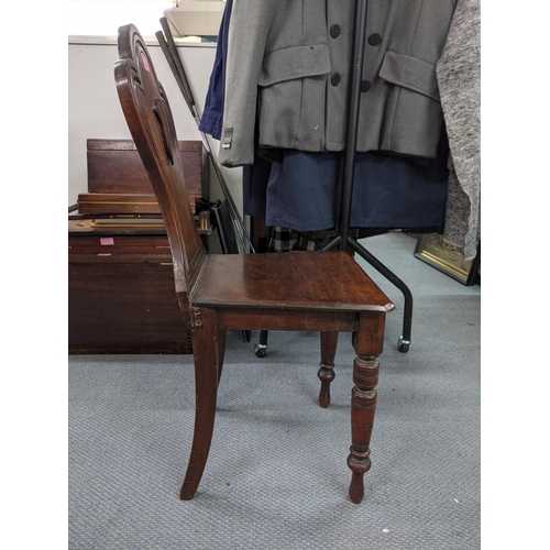 543 - A Victorian mahogany hall chair, the solid carved back with a shield crest motif with a solid seat s... 