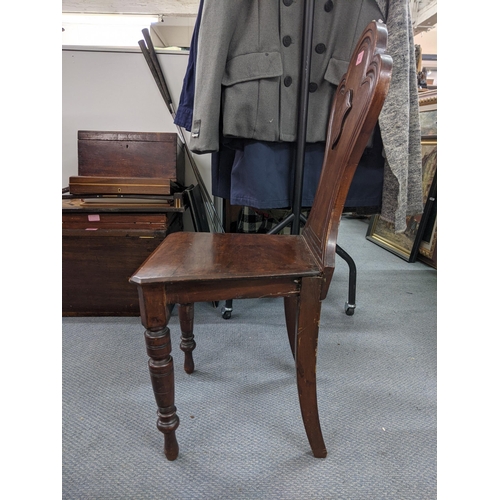 543 - A Victorian mahogany hall chair, the solid carved back with a shield crest motif with a solid seat s... 