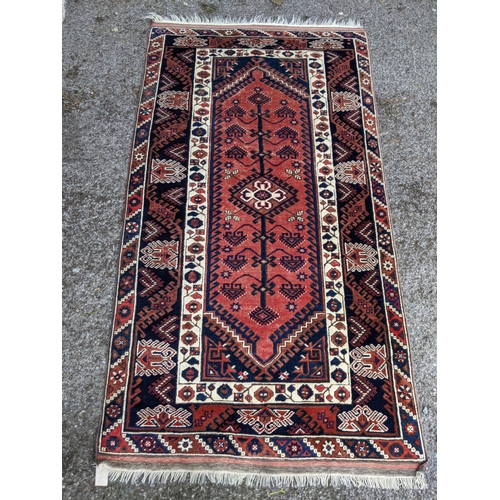 544 - A Turkish rug, the symmetrical blue abstract design on a red background with a central motif having ... 