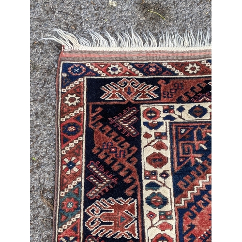 544 - A Turkish rug, the symmetrical blue abstract design on a red background with a central motif having ... 