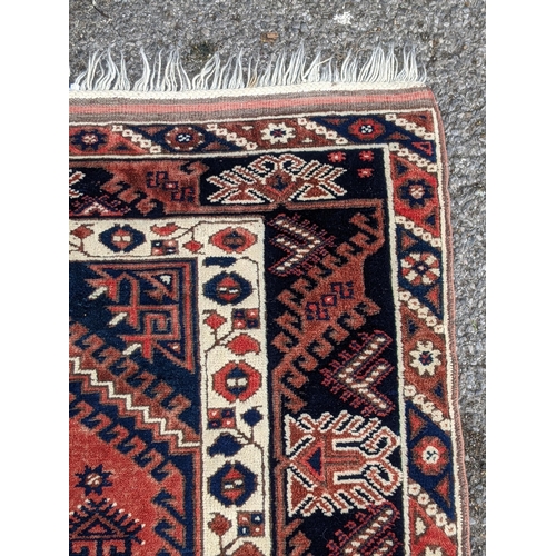 544 - A Turkish rug, the symmetrical blue abstract design on a red background with a central motif having ... 